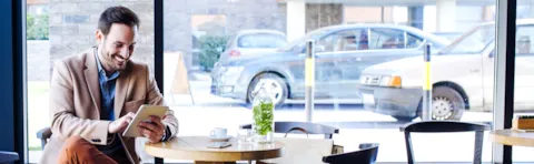Man sitting in coffee shop, drinking espresso coffee, usinf a tablet